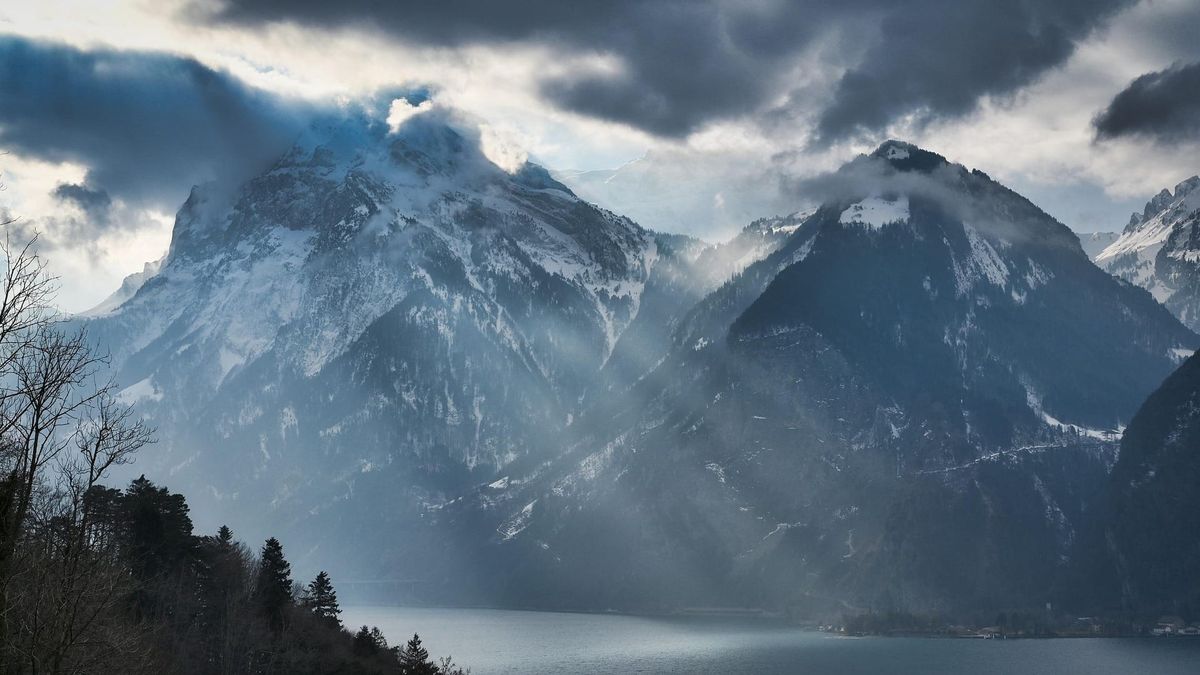 Dunkle Sturmwolken über schneebedeckten Bergen am Vierwaldstättersee in der Zentralschweiz. Symbolbild.