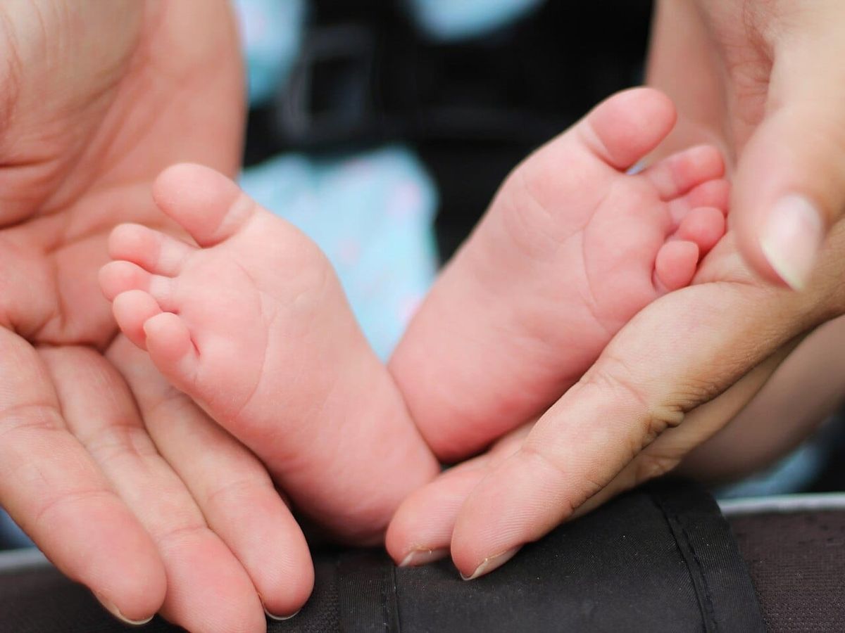Babyfüsse in den Händen einer Mutter. Symbolbild; keine Darstellung einer diagnostizierten Erkrankung.