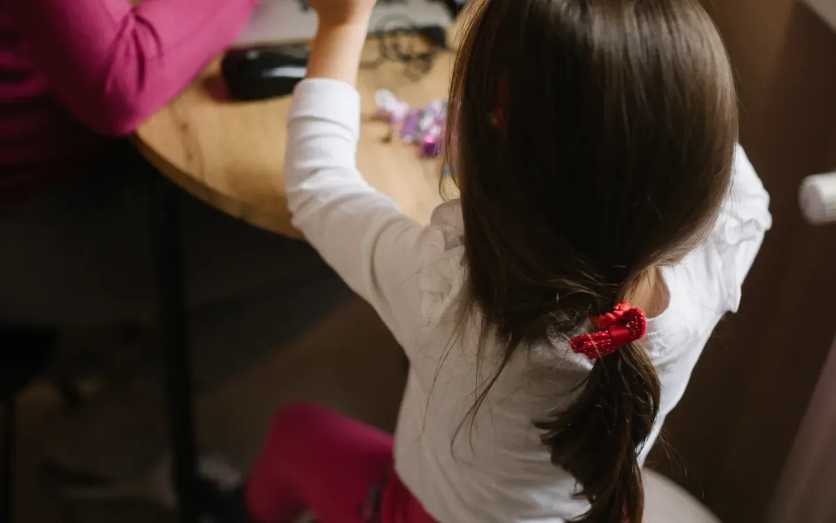 Elternteil arbeitet am Laptop, während ein Kind zu Hause spielt