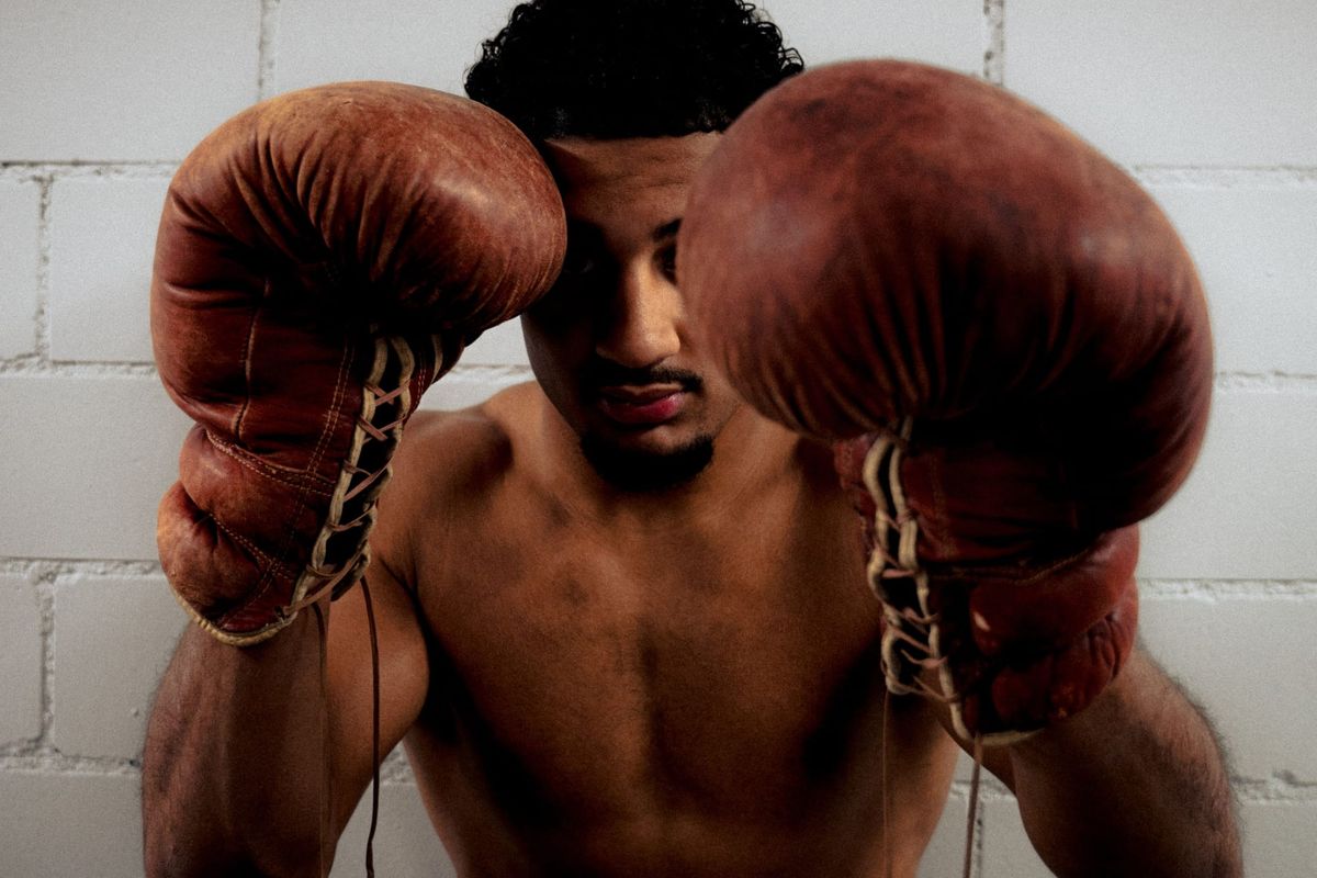Alpha Amadou Käser im Porträt mit erhobenen braunen Boxhandschuhen