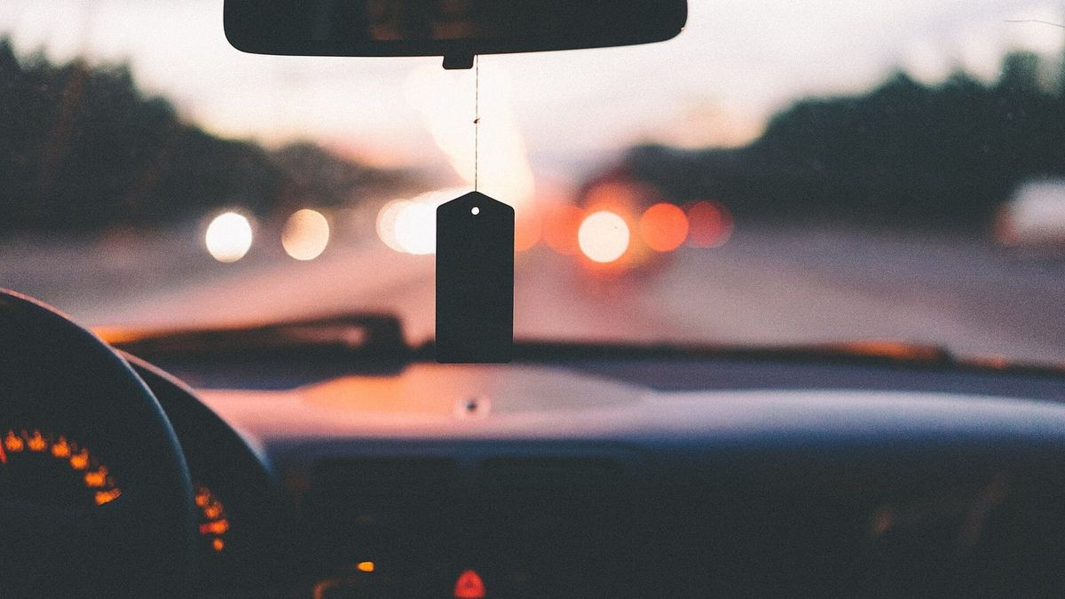 Blick über ein Autoarmaturenbrett auf eine Strasse bei Abendlicht