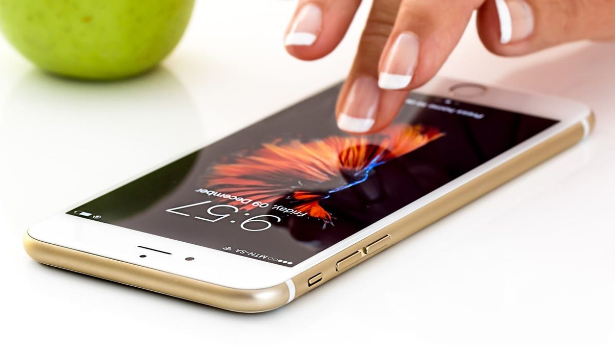 Eine Hand bedient ein Smartphone auf einem Tisch