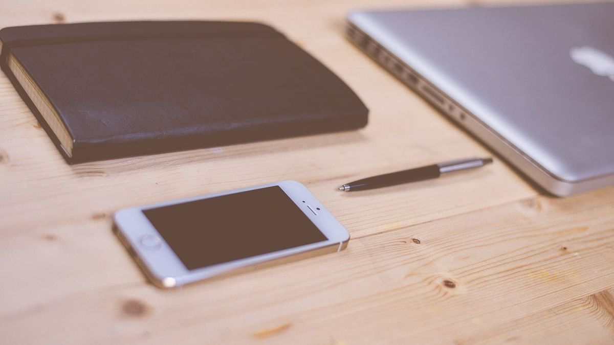 Smartphone neben Notizbuch und Stift auf einem Schreibtisch