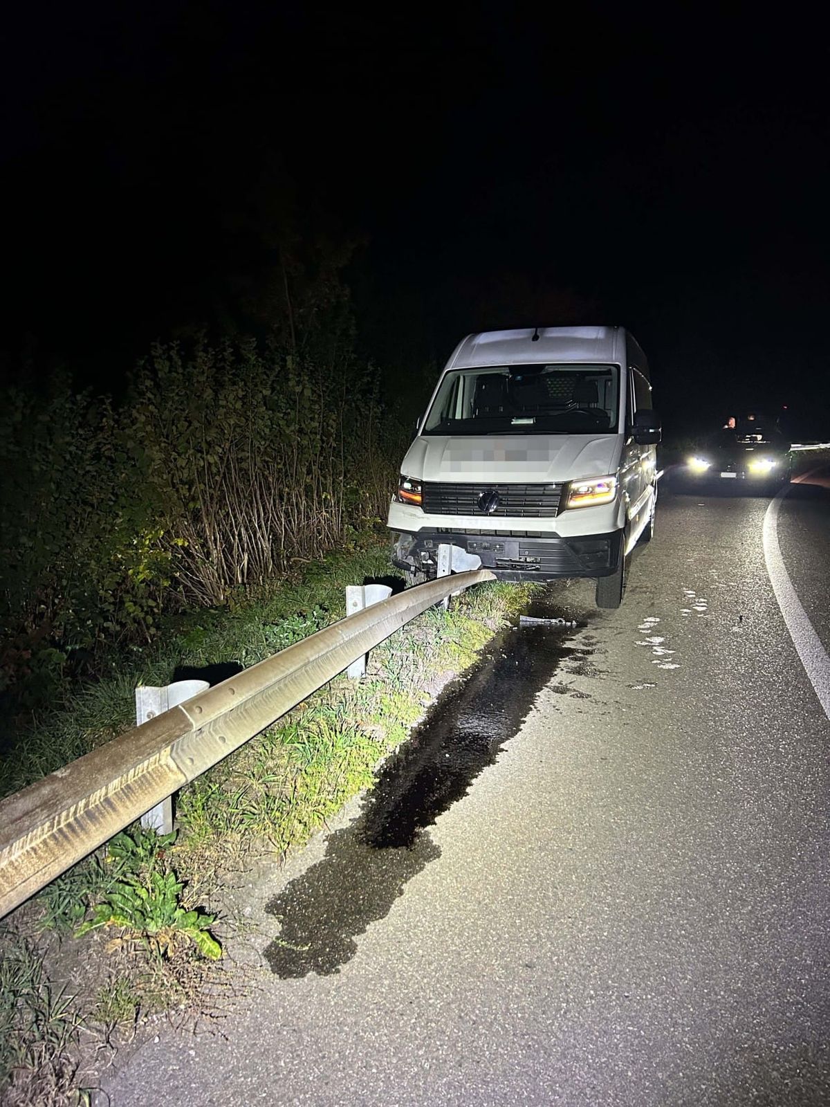 Weisser Lieferwagen steht auf einer Leitplanke und Öl fliesst auf den Boden.