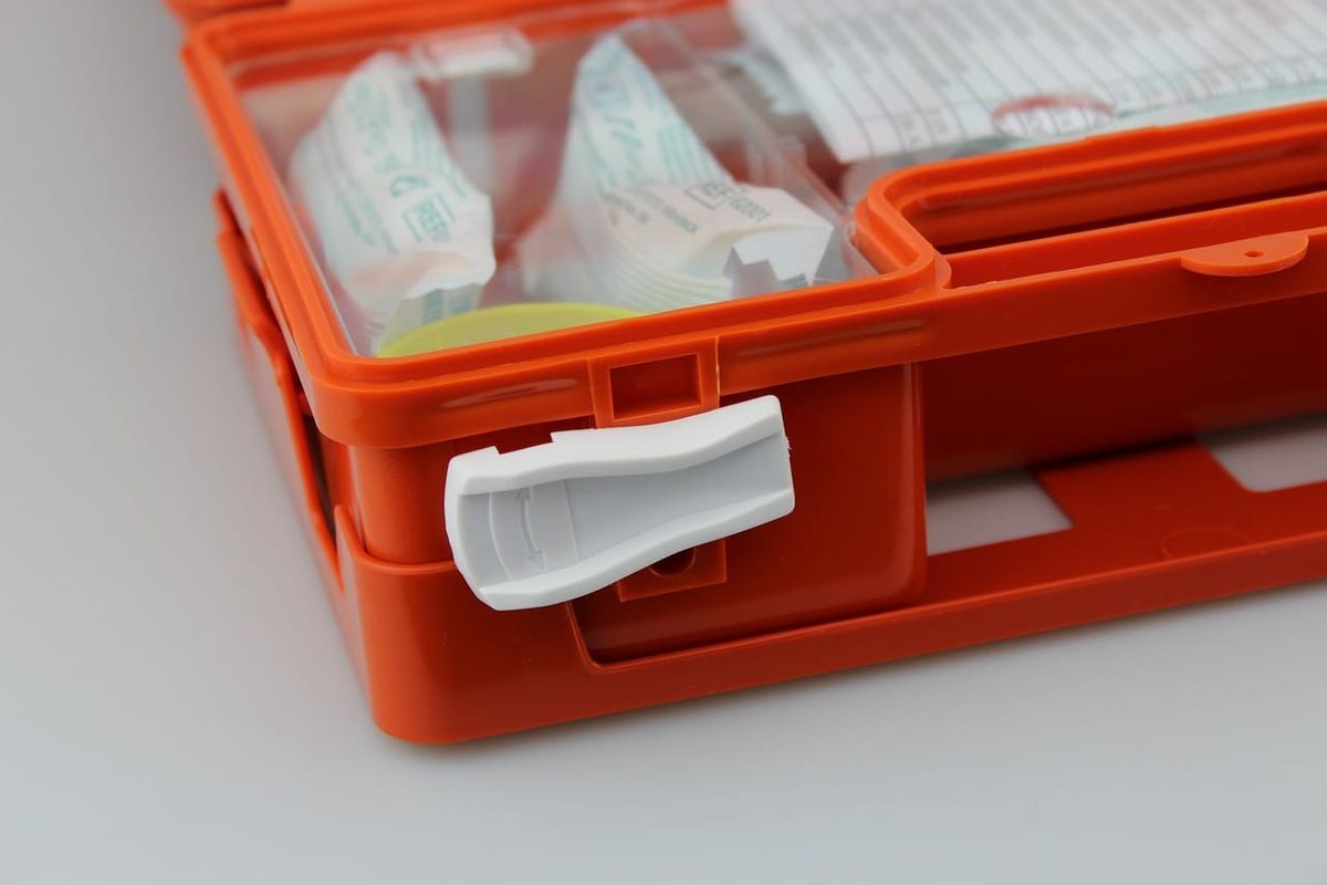 Symbolbild: Nahaufnahme eines geschlossenen orangen Erste-Hilfe-Kastens mit weißen Verschlüssen