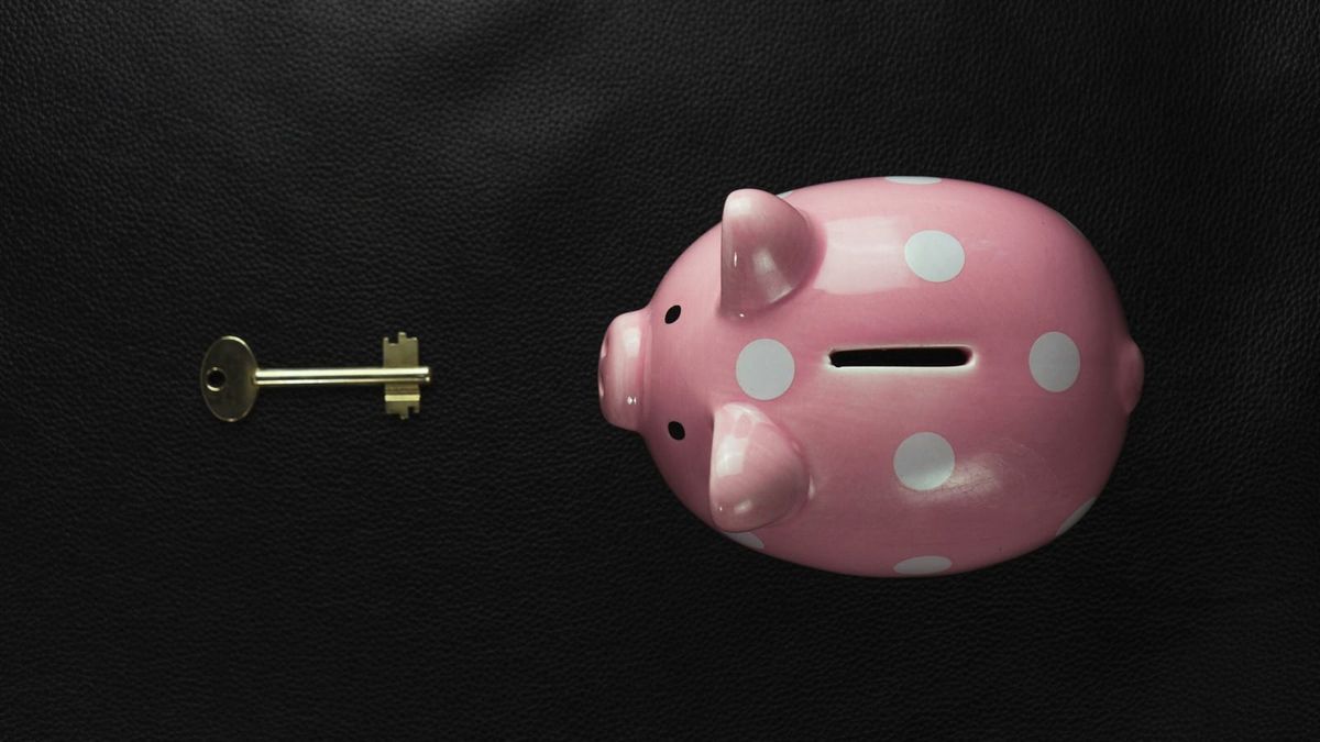 Rosa Sparschwein und ein Schlüssel auf dunklem Untergrund