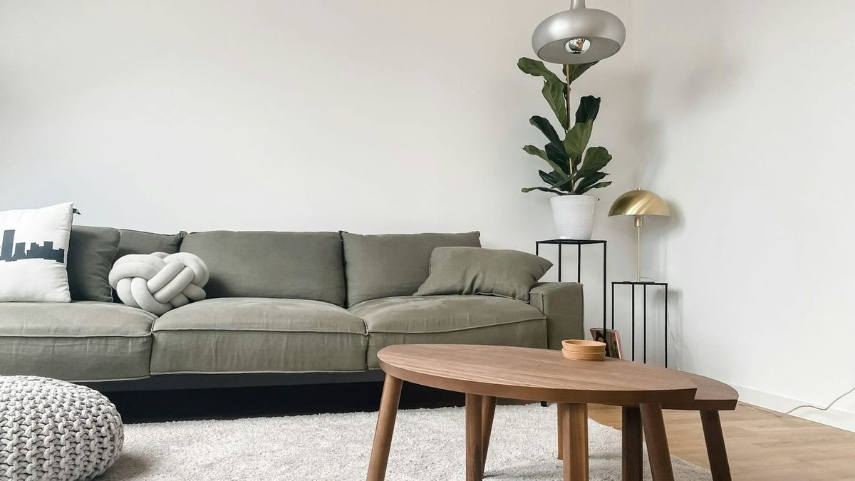 Helles Wohnzimmer mit grauem Sofa und kleinen Holztischen