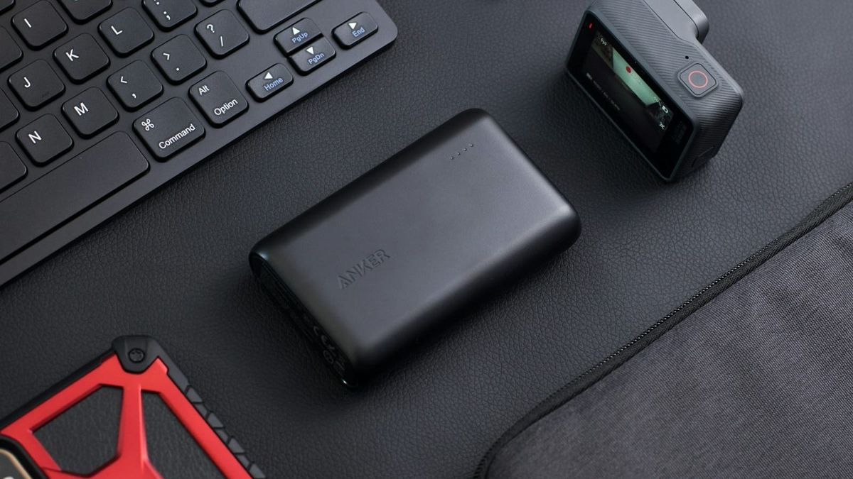 Schwarze Powerbank neben Tastatur und weiteren mobilen Geräten