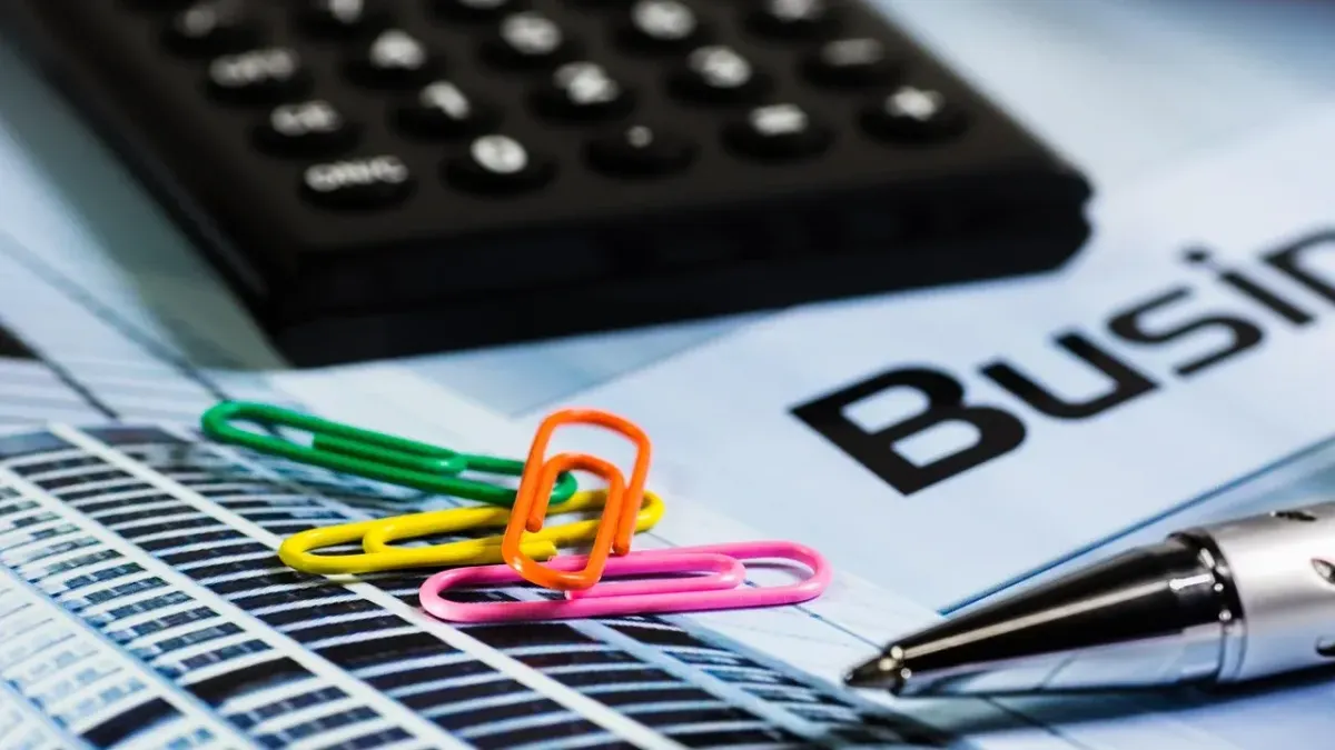 Taschenrechner, Büroklammern und Stift auf einem Schreibtisch