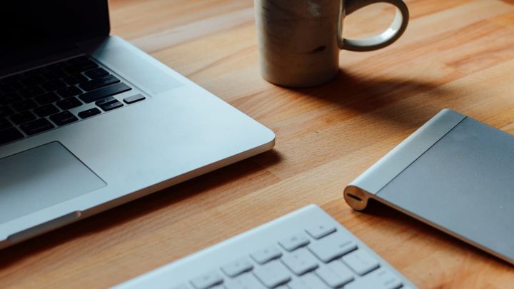 Laptop, Notizbuch und Kaffeetasse auf einem Schreibtisch