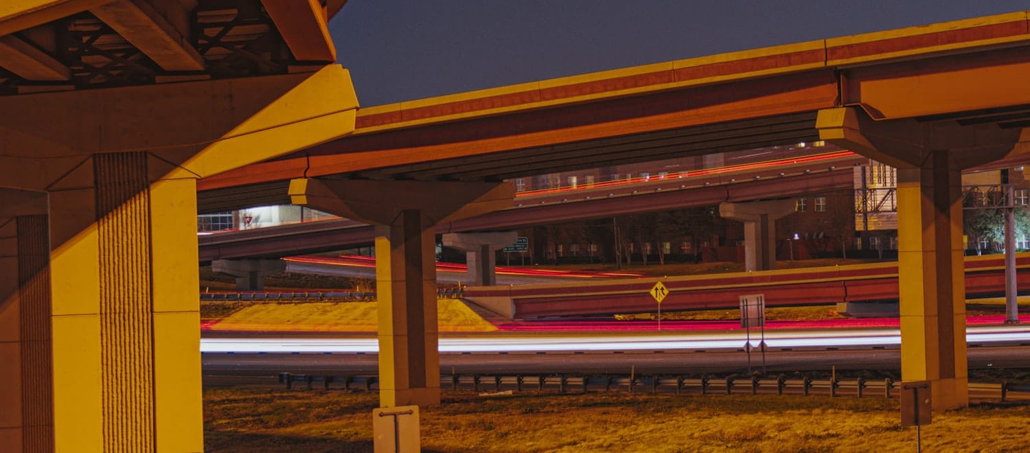 Multi-level highway interchange at night — the layer above the independent roadways is where the value routes