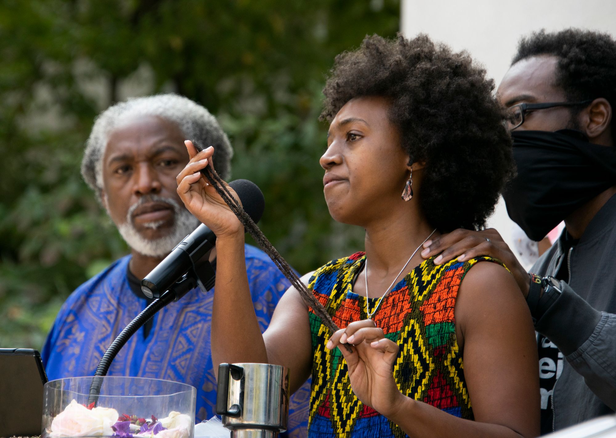 Nakia Porter at a rally in Sacramento, holding up dreadlocks she said were ripped from her head