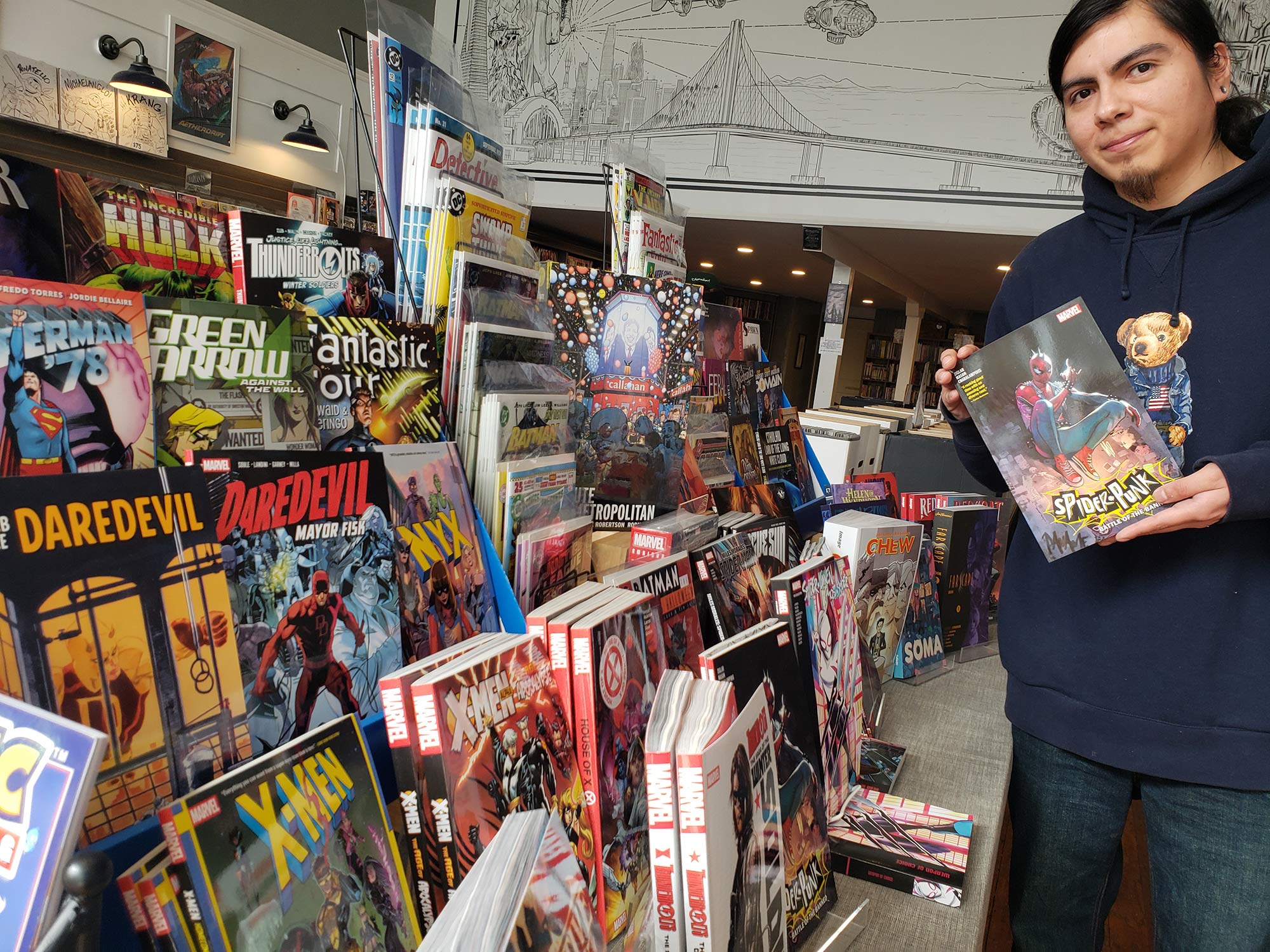 Joe Gomez stands with a rack of new comics at Zeppelin Comics in Benicia.
