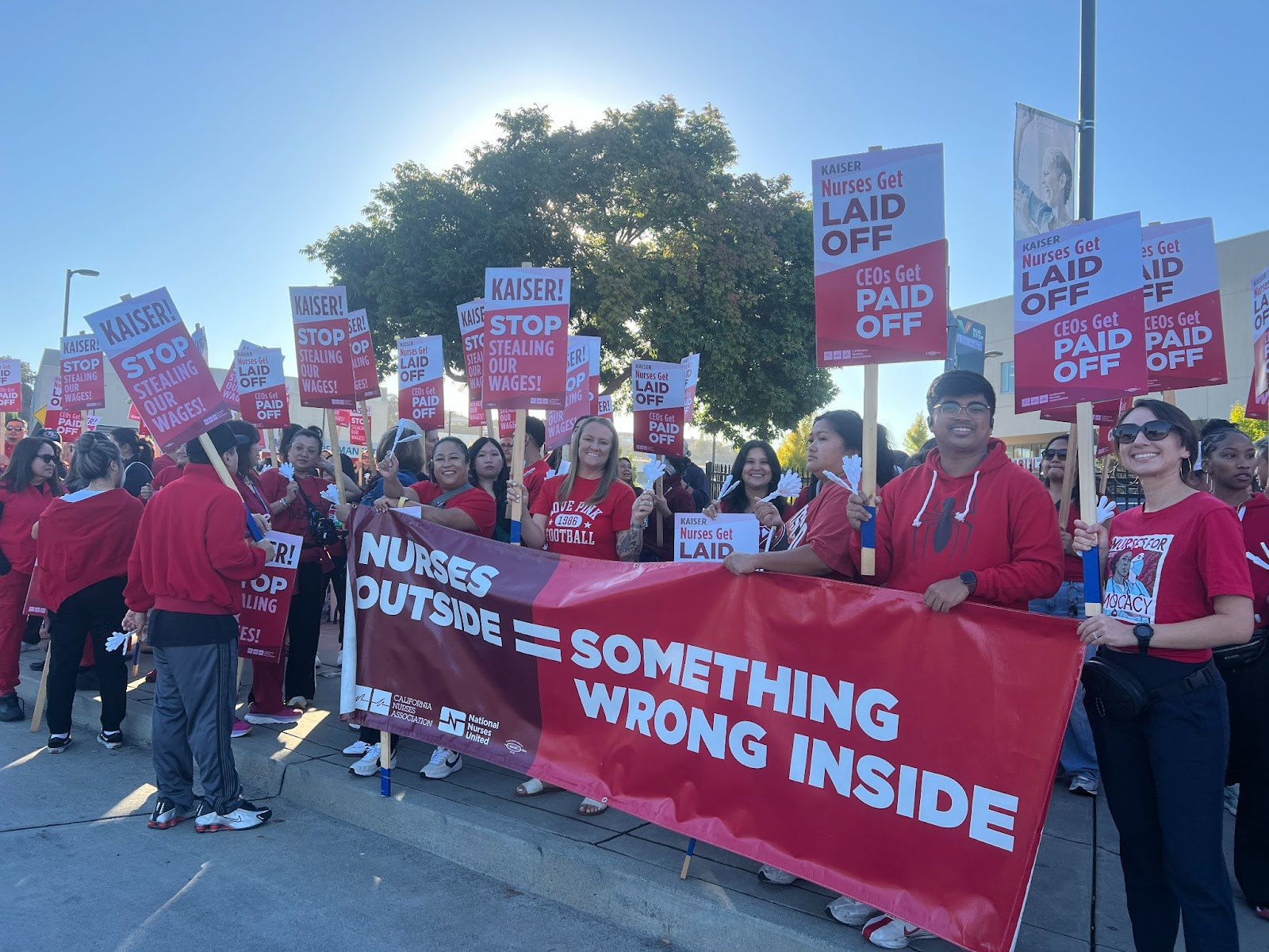 Nurses pose with signs outside of Kaiser. 