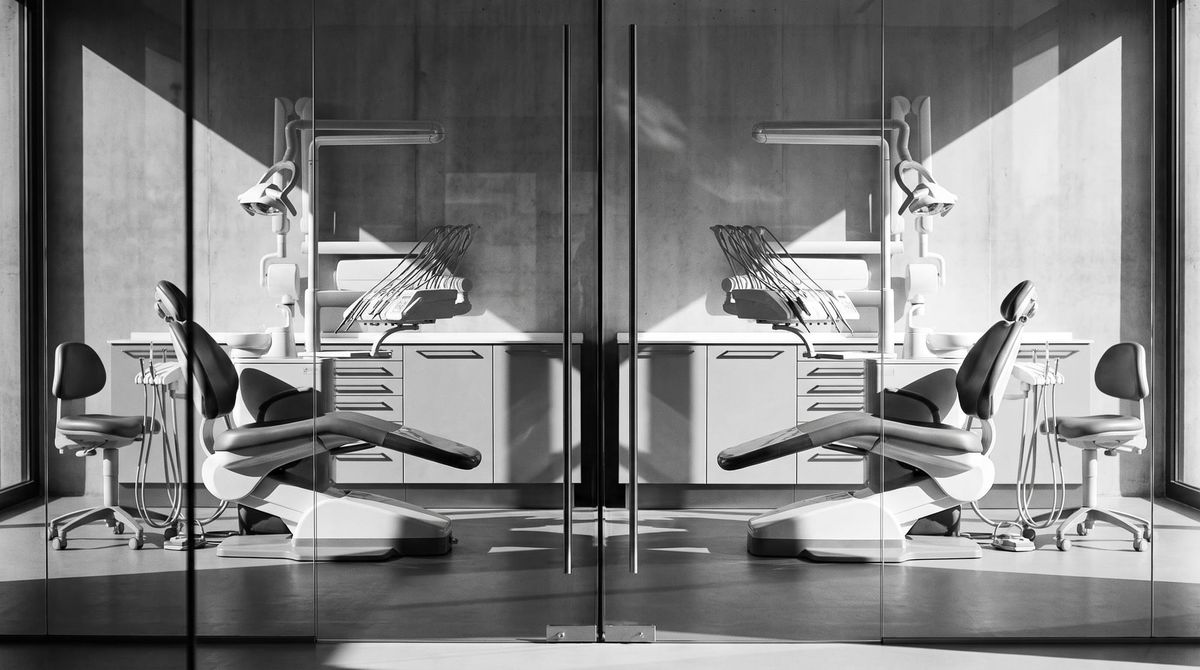 Two identical dental operatories side by side through a glass partition