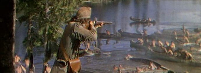 A pioneer-era American soldier aims his rifle toward a river, into which dozens of Native American men are trying to escape.