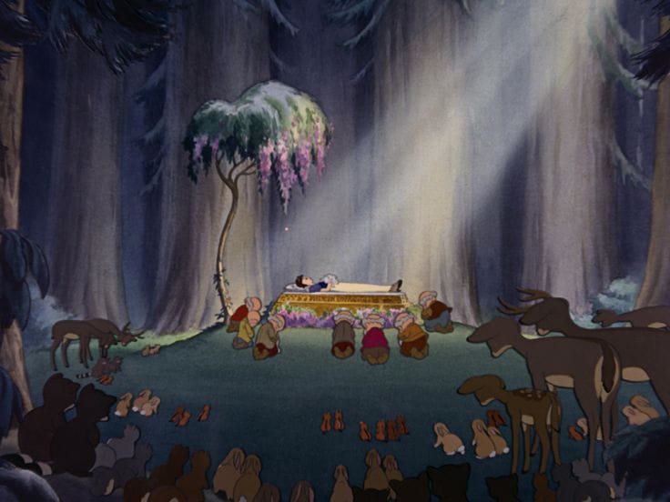 Tableau from Snow White and the Seven Dwarfs. In a clearing in the woods, with rays of sunlight shining on her, Snow White lays in repose. Around her the dwarfs kneel in sadness, as do the woodland creatures on the perimeter.