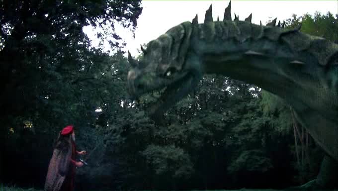 A man in generic fantasy cap and cloak holds a sword out to a giant, cheaply-rendered lizard.