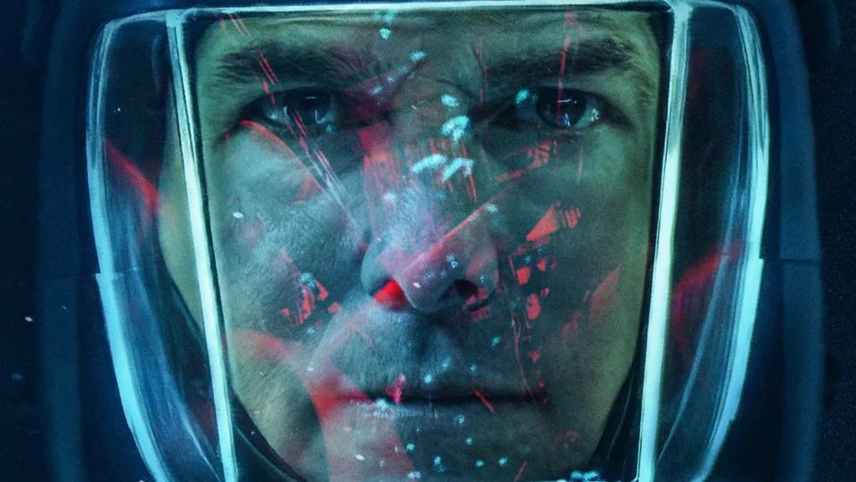 Tom Cruise, wearing a thick diving helmet, with red lights reflecting off the glass.