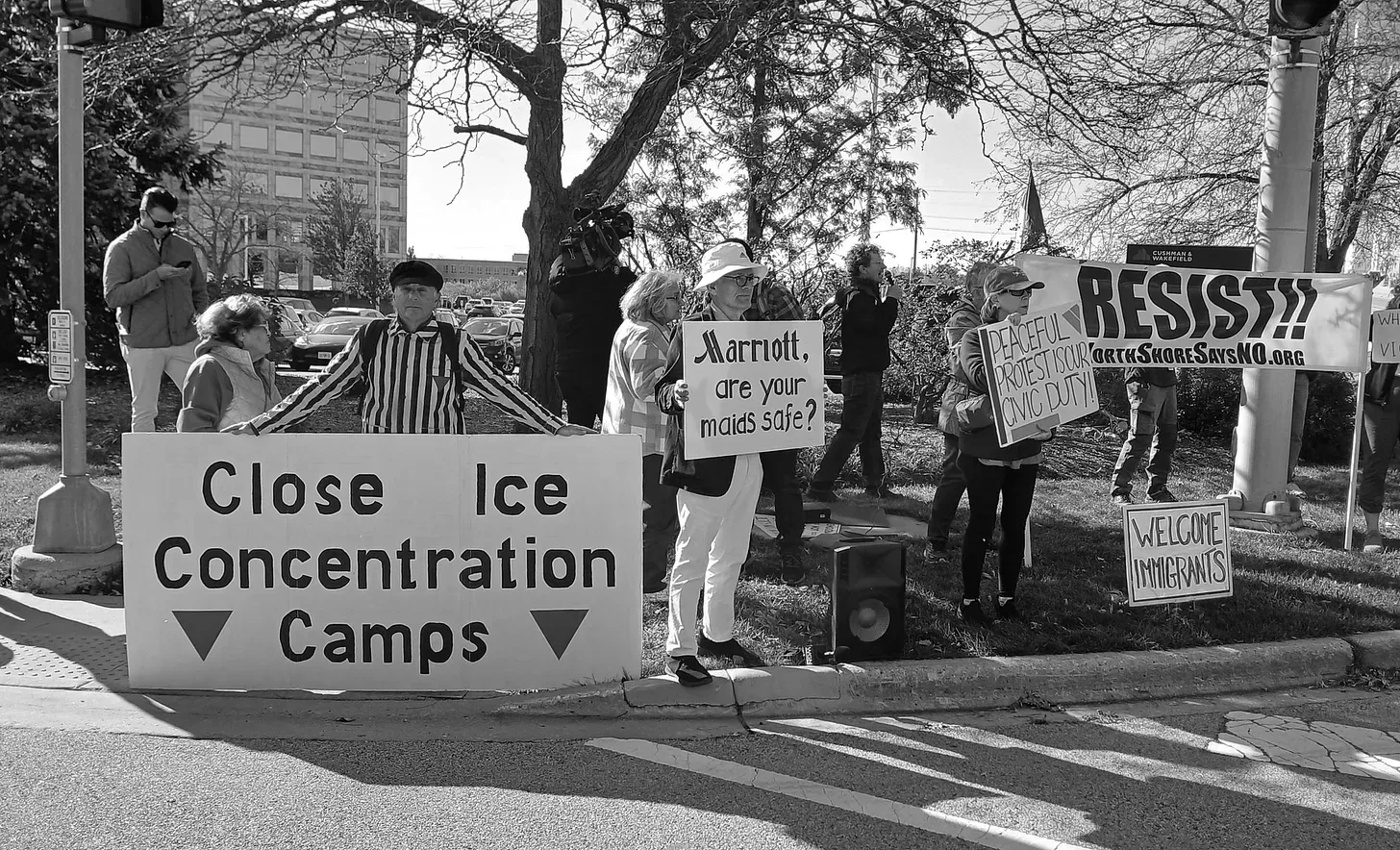 Black and white photo of protestors holding signs with messages such as "Close ICE concentration camps" and "Welcome immigrants"