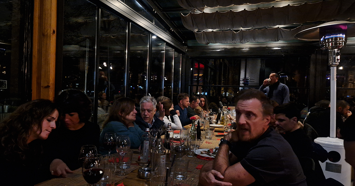 Participants of the conference sitting on a long dinner table talking to each other.