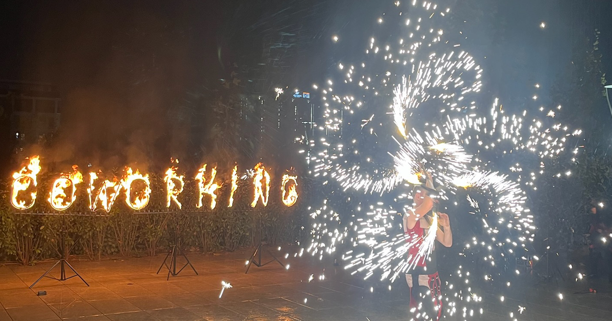 Coworking sign on fire with firethrowers next to it.