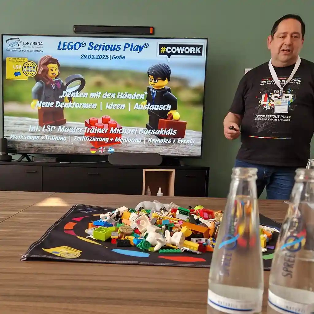 Person sitting next to a screen showing LEGO serious play method with legos in front of him.