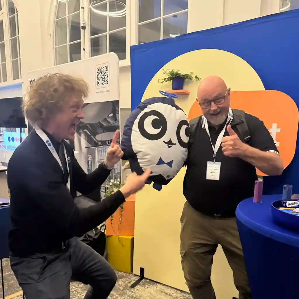 Two people holding the Cobot mascot and laughing.