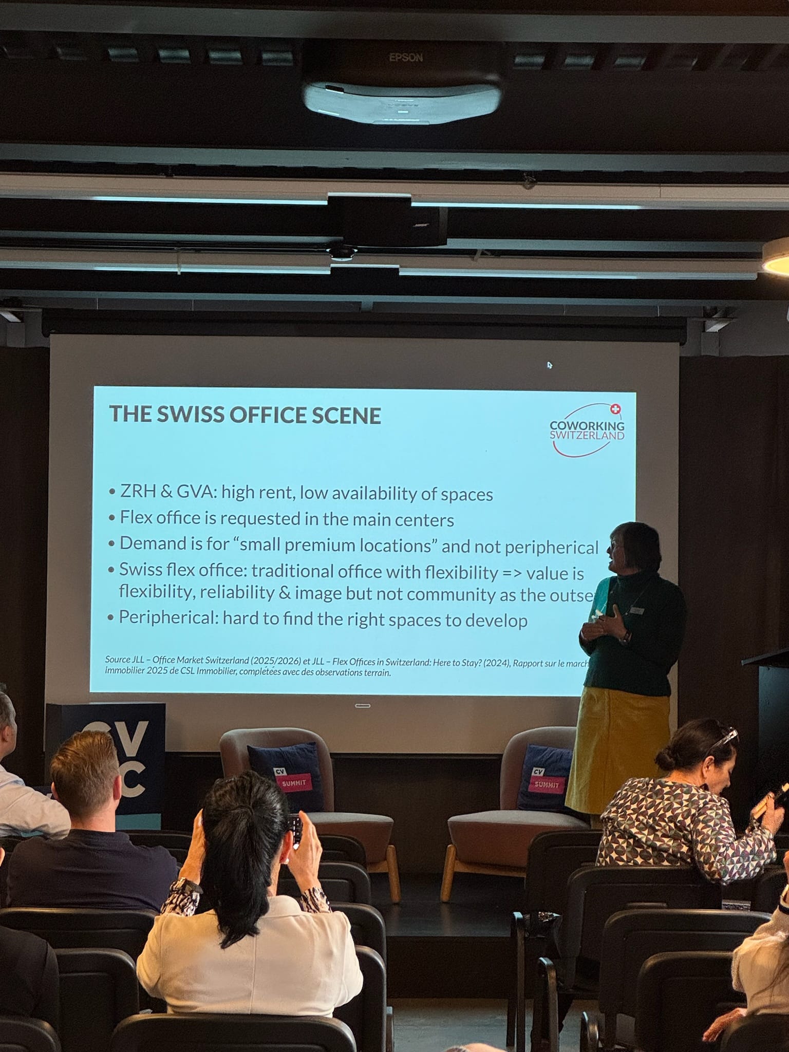Mélanie presenting "The Swiss Office Scene" slide at CV Labs, with audience members seated in front.