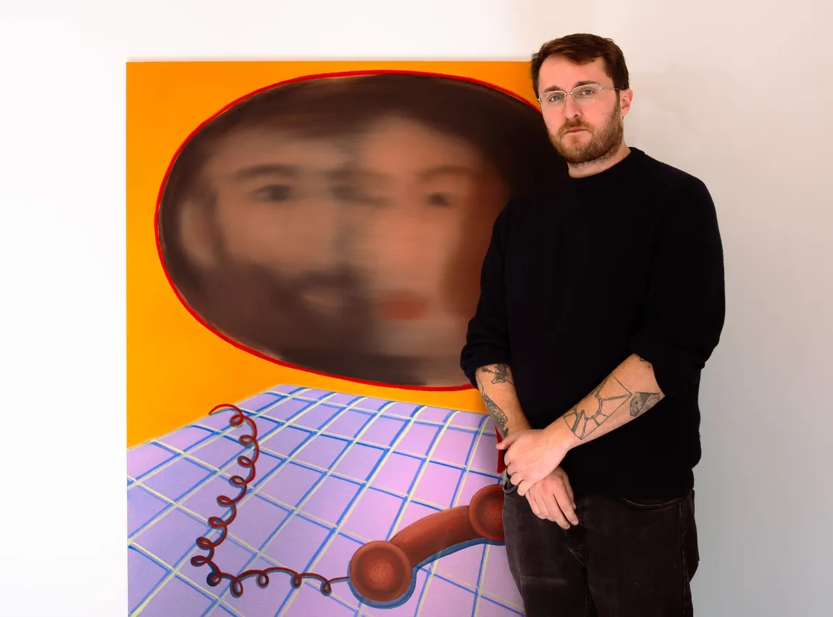 Hector Campbell stands beside a Kyveli Zoi painting featuring a red telephone at Soup Gallery.