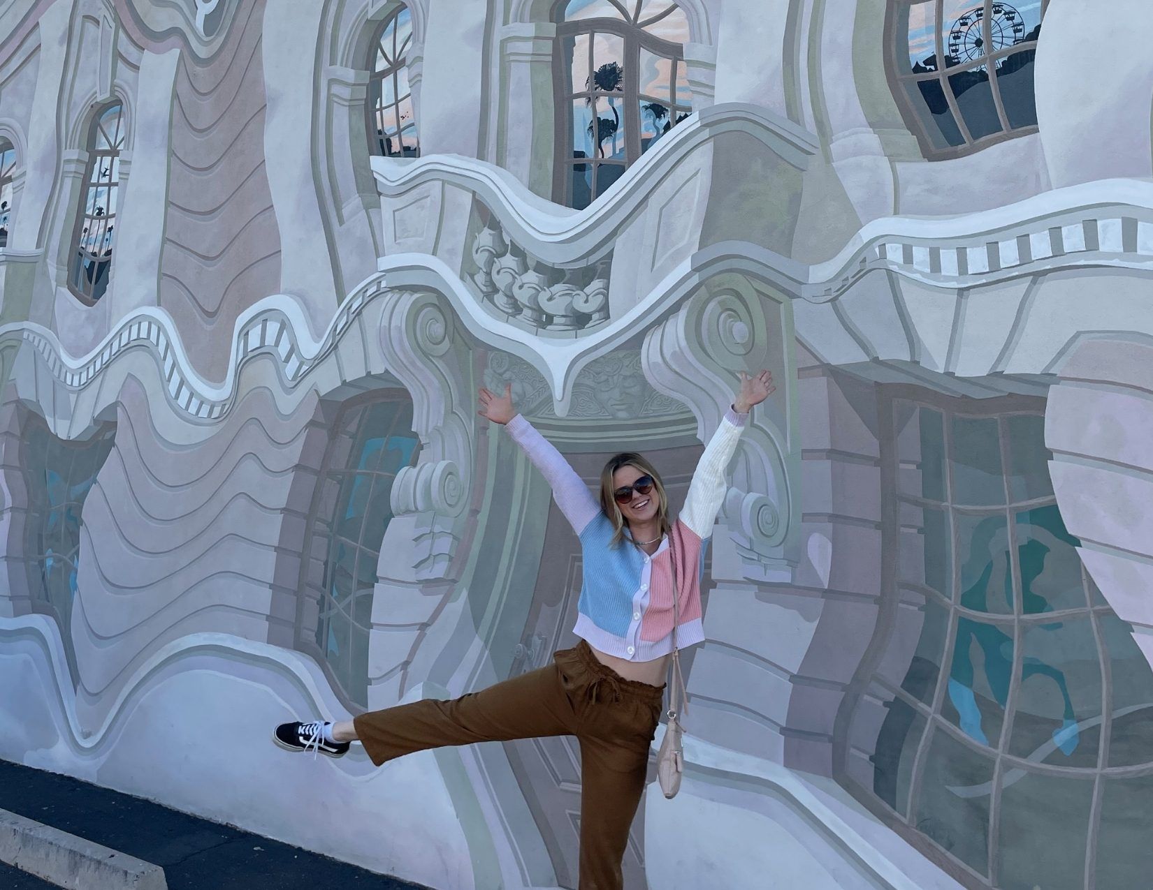a girl with her arms up posing in front of funky, delusional mural in Downtown Mesa, Arizona