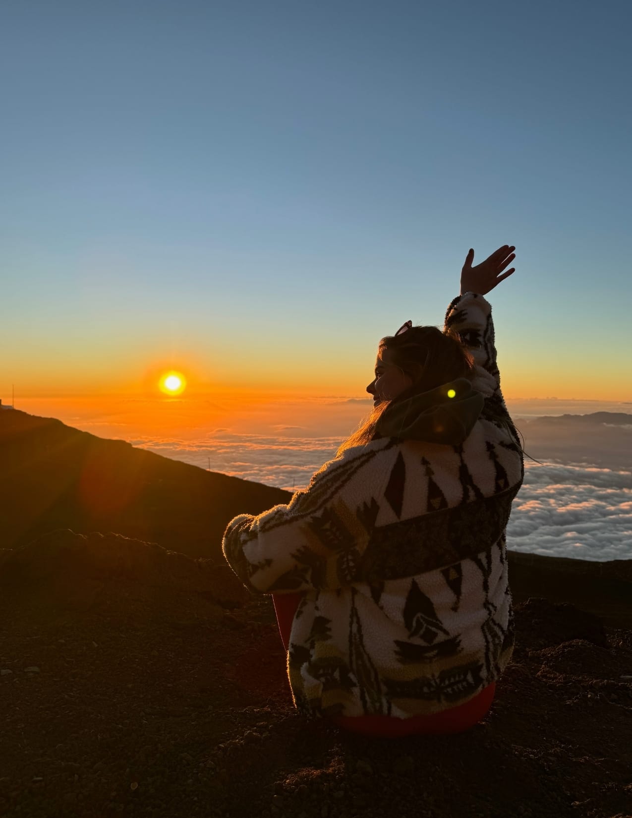 young woman looking at the sunset on top of Haleakala in Maui, Hawaii
