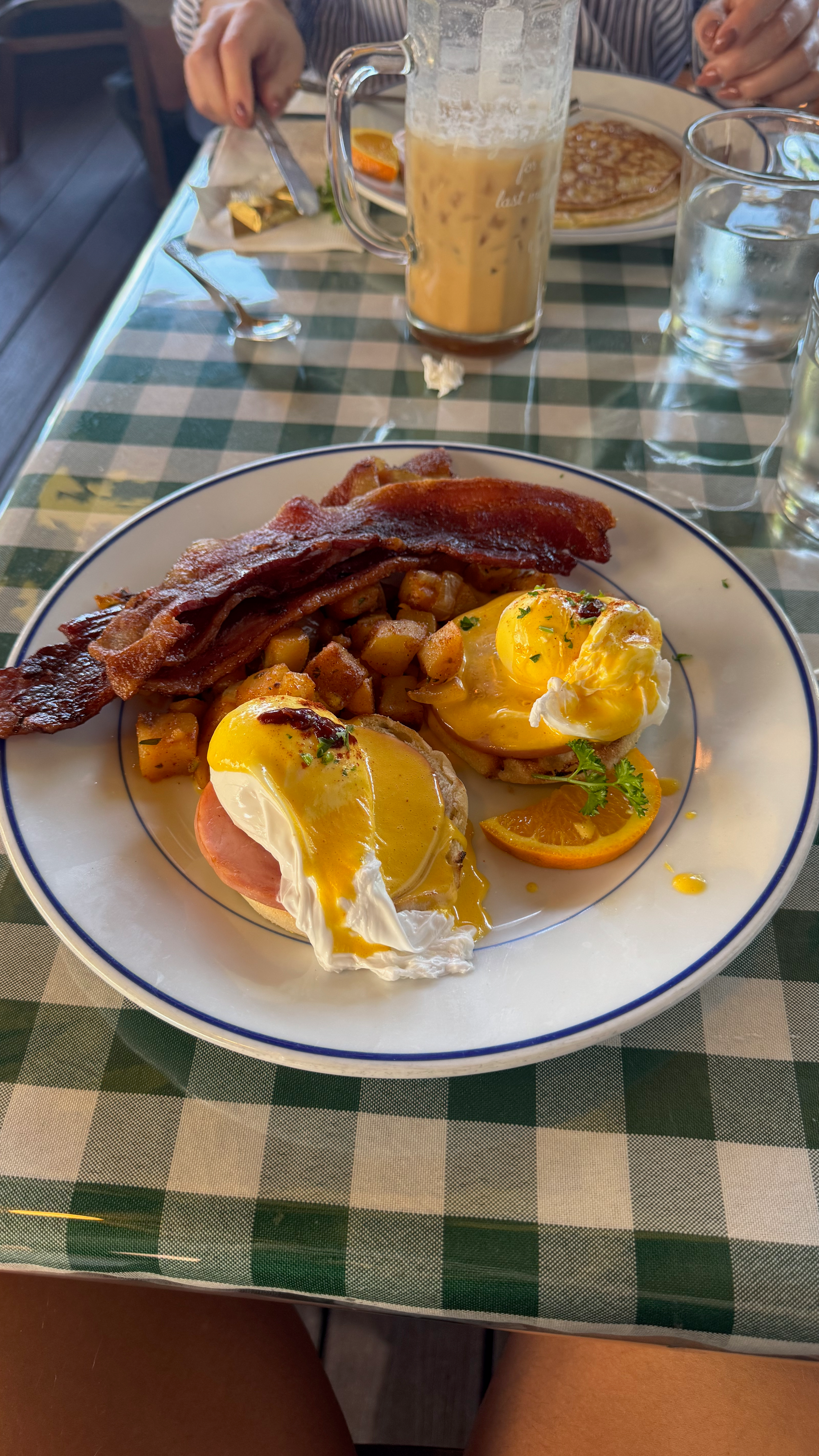 a plate of food with orange slices, Eggs Benedict hash browns and thick cut bacon at Jailhouse Cafe in Moab, Utah