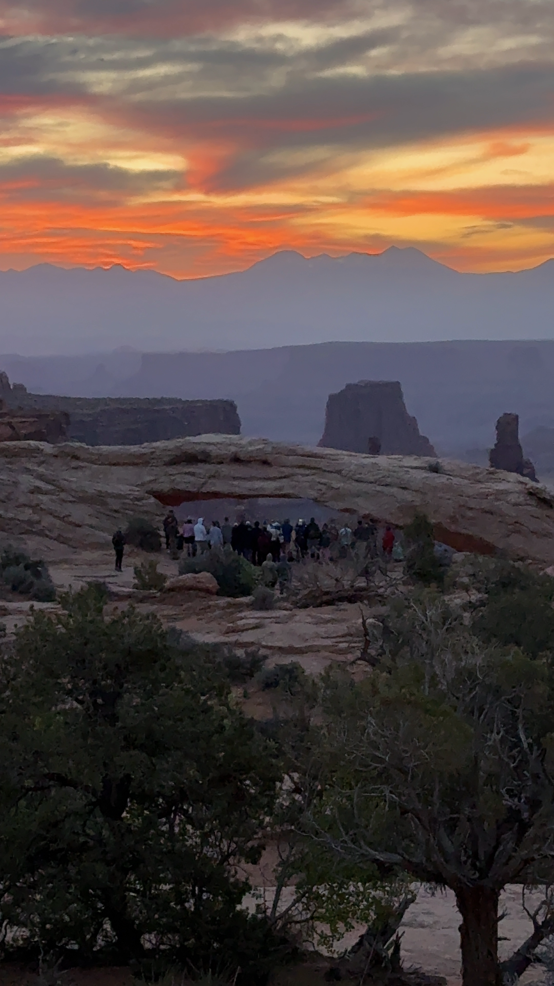 Gathering of people waiting for sunrise by the Mesa Arch at the Mesa Arch Trailhead in Moab, Utah 