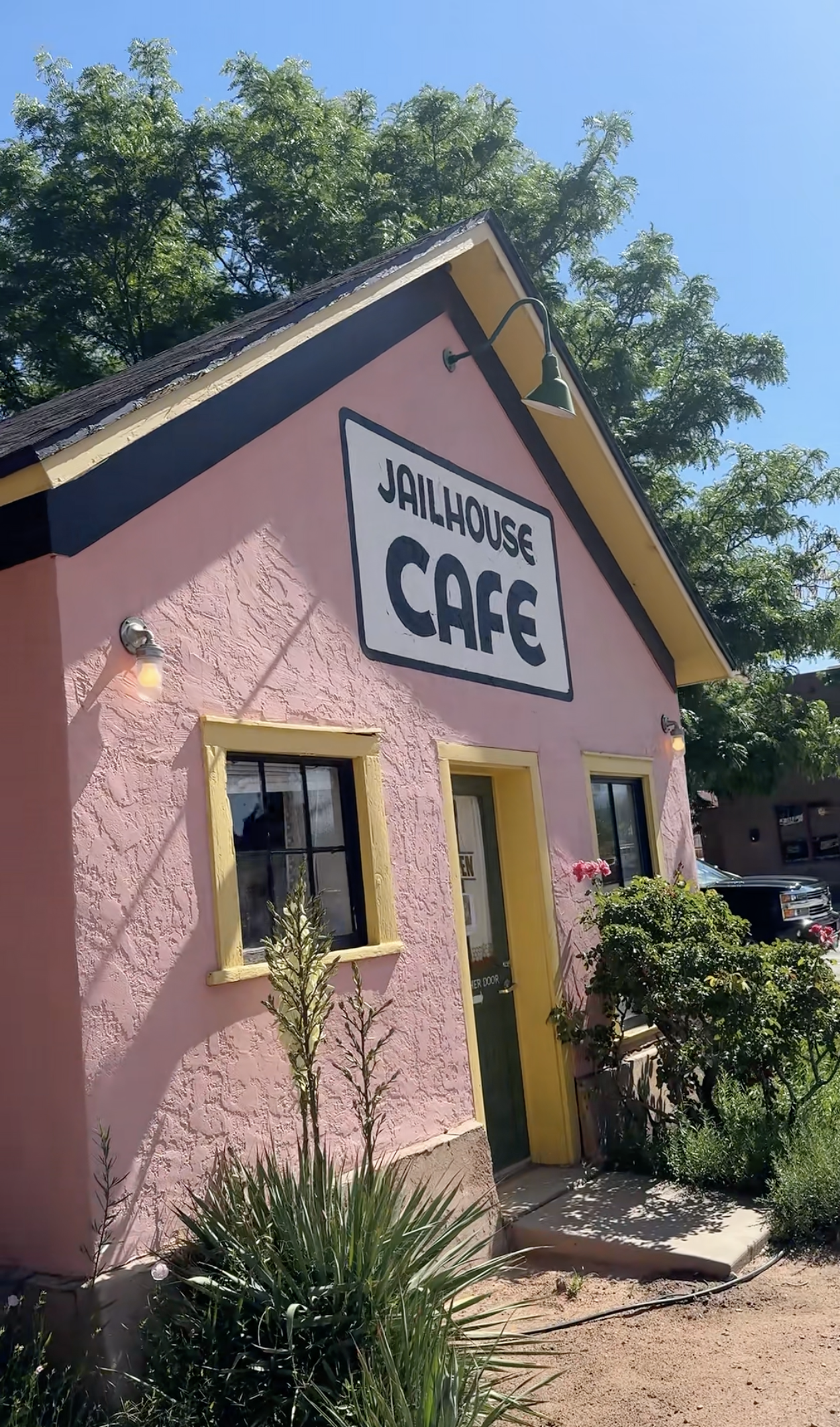 Breakfast restaurant with pink paint and yellow window trim and roof with a sign that reads "Jailhouse Cafe" in Moab, Utah