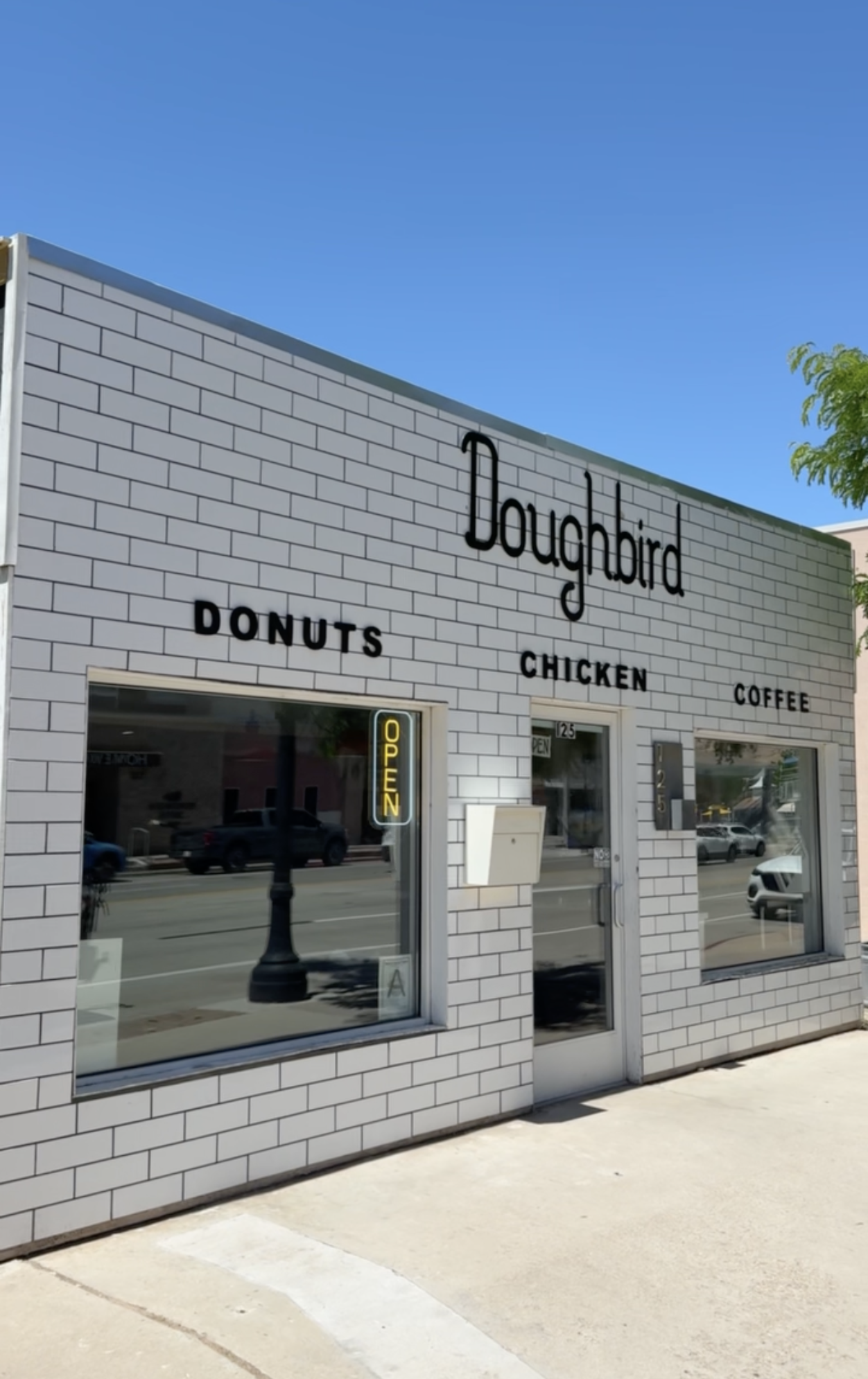 White building with signs that read "Doughbird Donuts Chicken and Coffee" at Doughbird Donuts in Moab, Utah