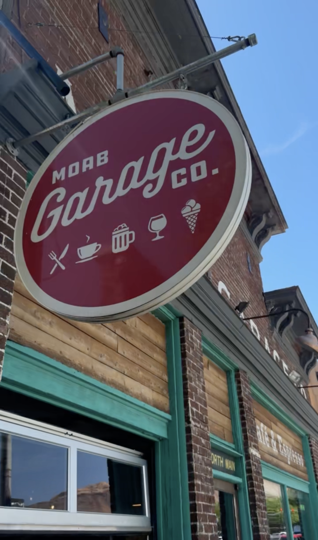 Red and white circular sign that reads "Moab Garage co." at Moab Garage Co. in Moab, Utah