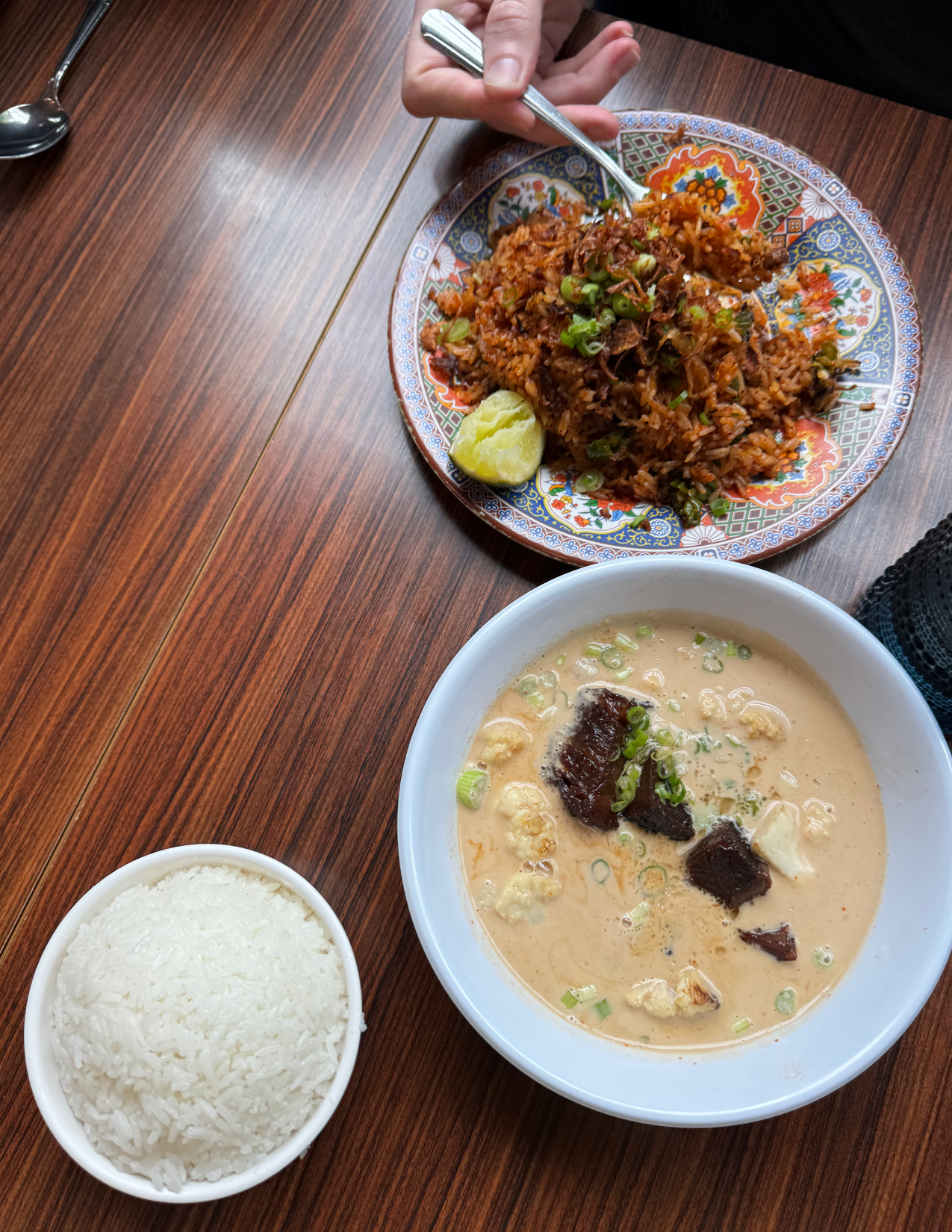 a bowl of curry, a bowl of fried rice, and a bowl of white rice on a table at EEM in Portland, Oregon