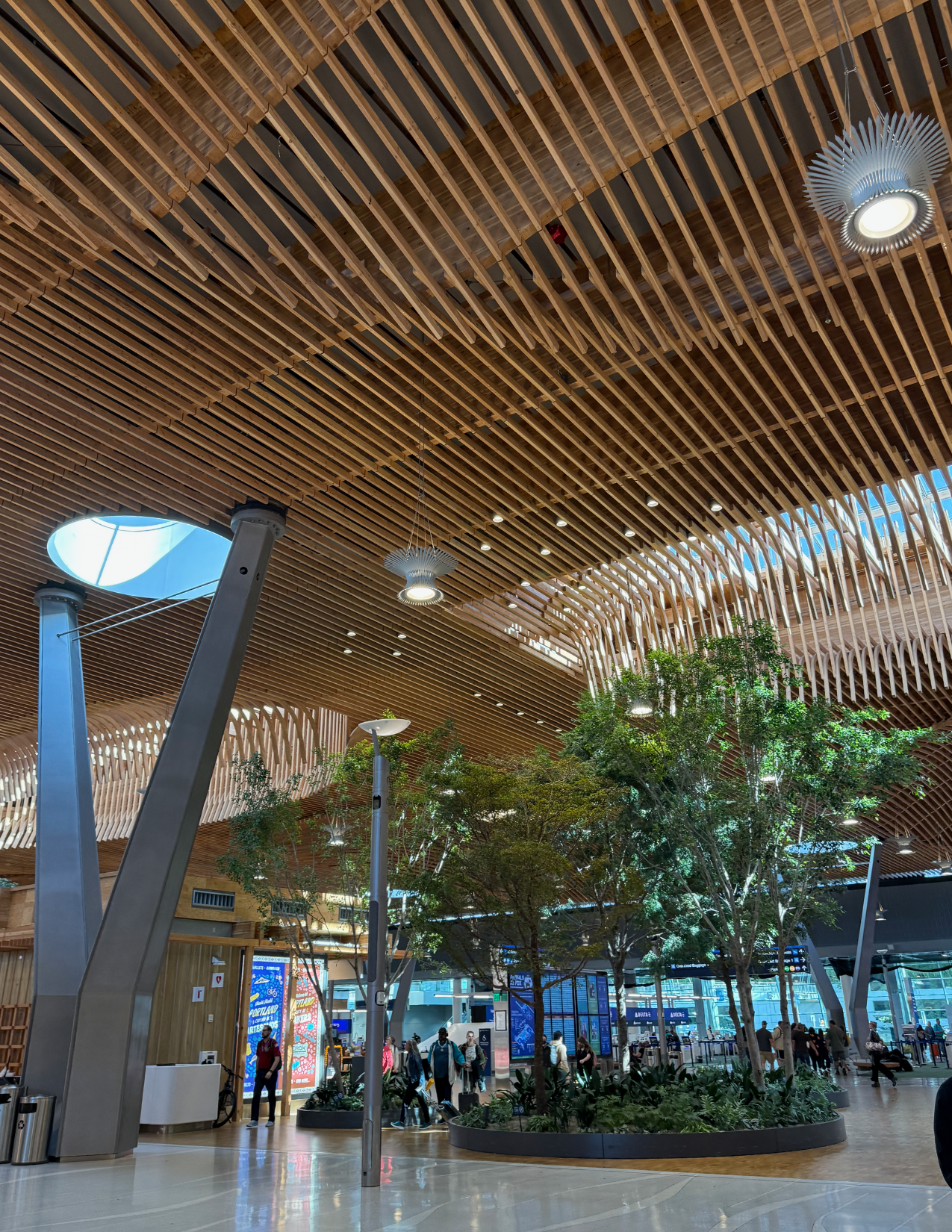 Wooden ceiling of Portland International Airport with trees and people walking around