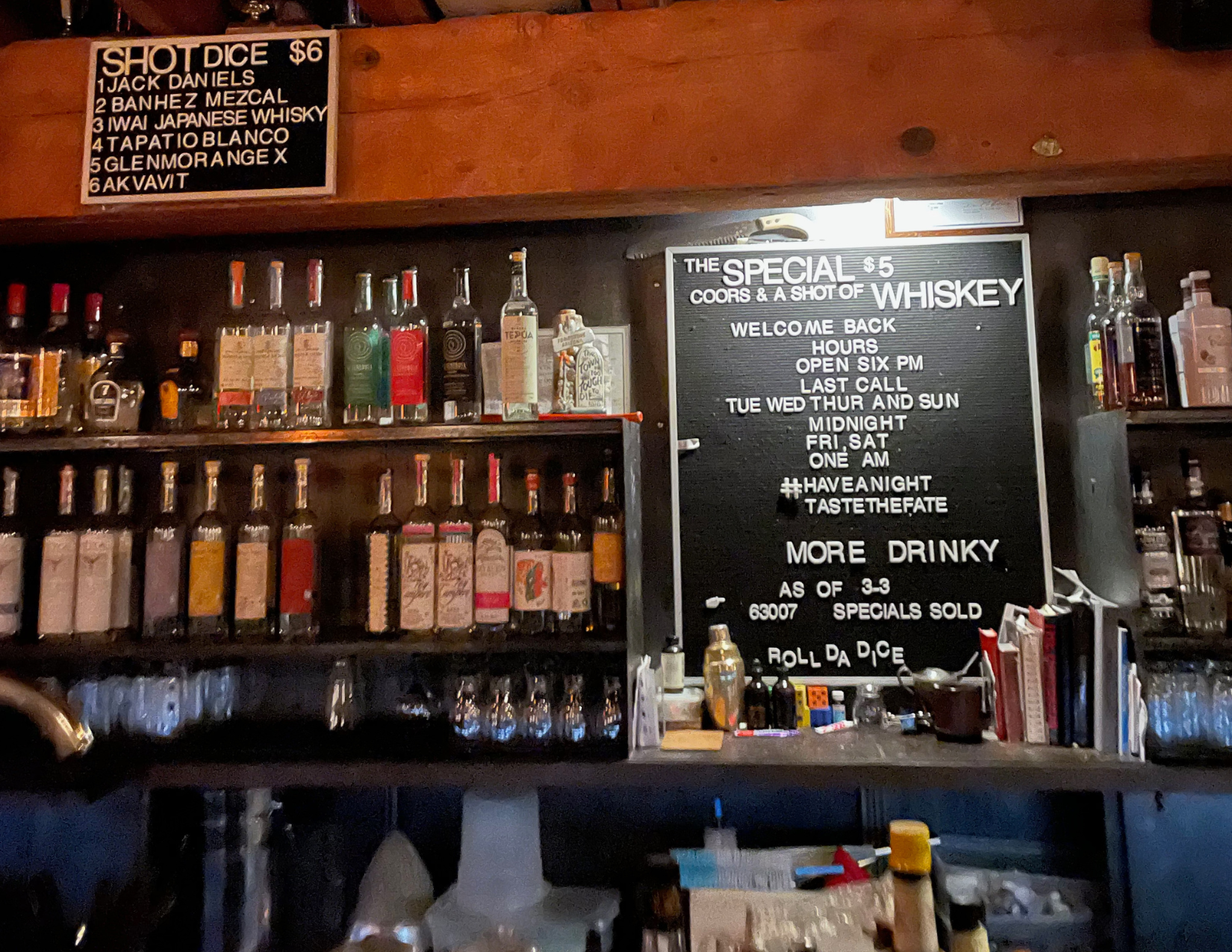 Bar shelves stocked with liquor bottles inside Tough Luck Club, a hidden basement speakeasy in Tucson featuring its signature dice roll drink menu.