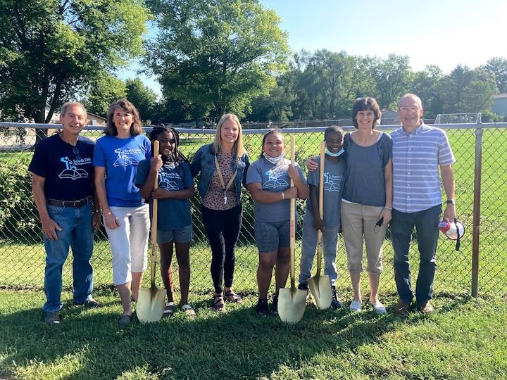Group of students and adults at groundbreaking ceremony for South Side Catholic School garden. Three golden shovels visible.