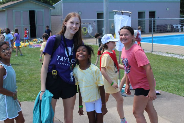 Campers of various ages smile near a swimming pool.
