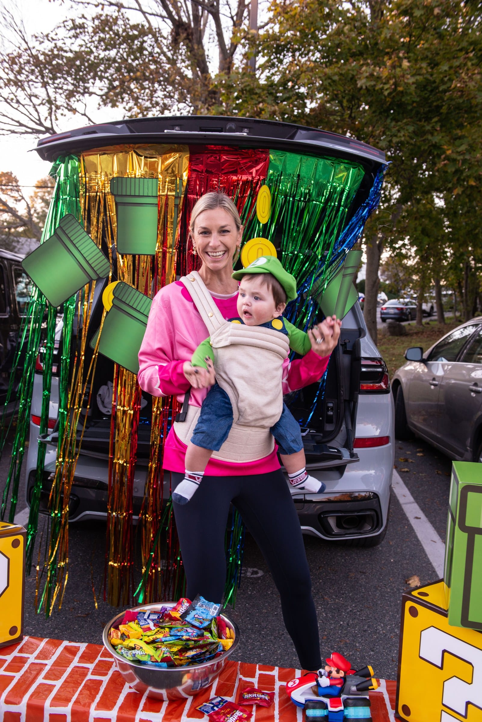 Luka Svirks, dressed as Luigi, is held by an adult in front of the Svirks family’s Super Mario-themed trunk during Glover School’s Trunk or Treat.