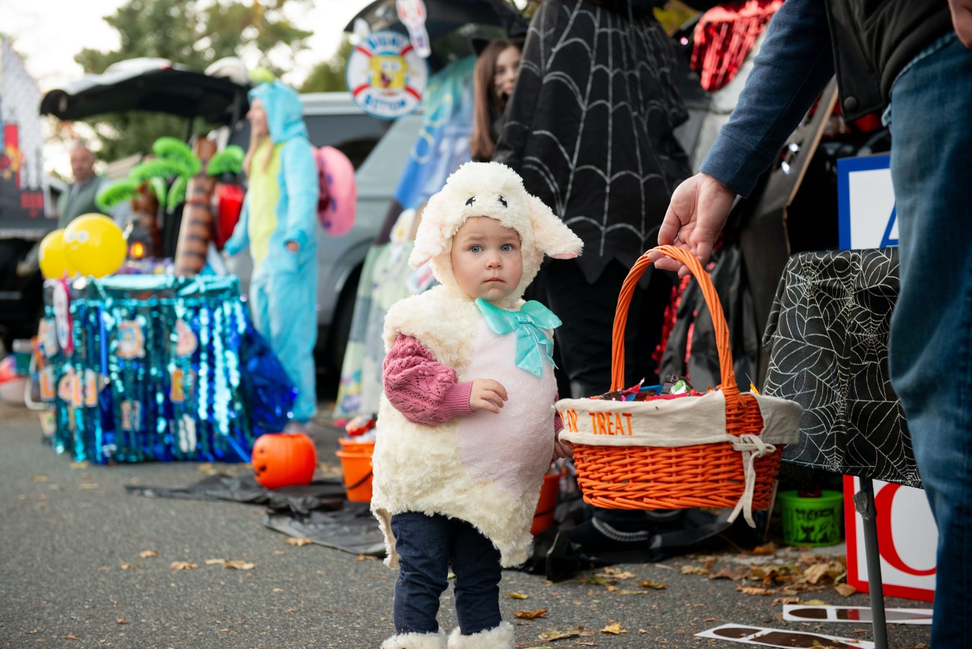 Catherine, dressed as a lamb, waits as an adult holds her treat basket at Glover School’s Trunk or Treat.