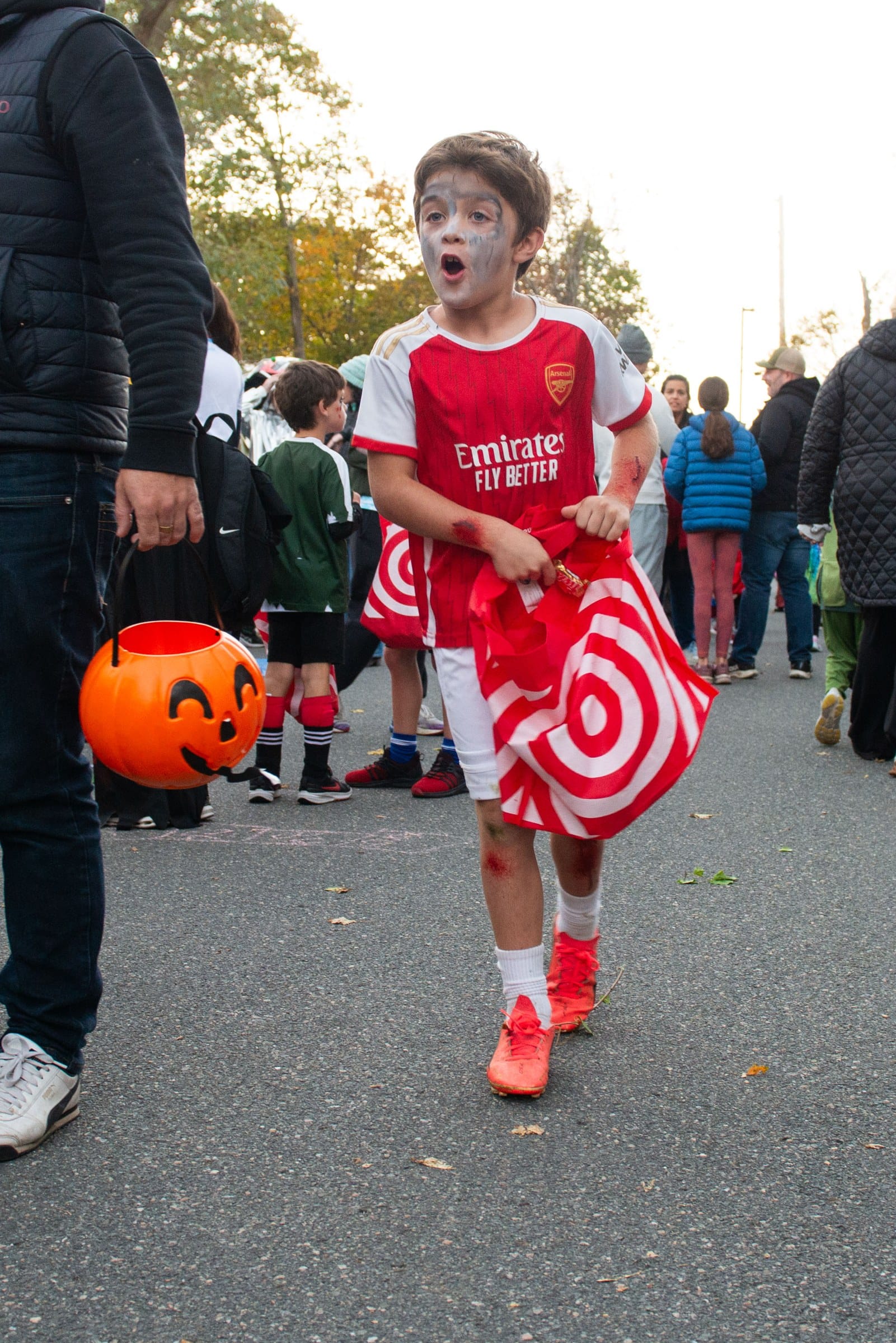 A trick-or-treater dressed as a zombie soccer player reacts while carrying a bag of candy at Glover School’s Trunk or Treat.