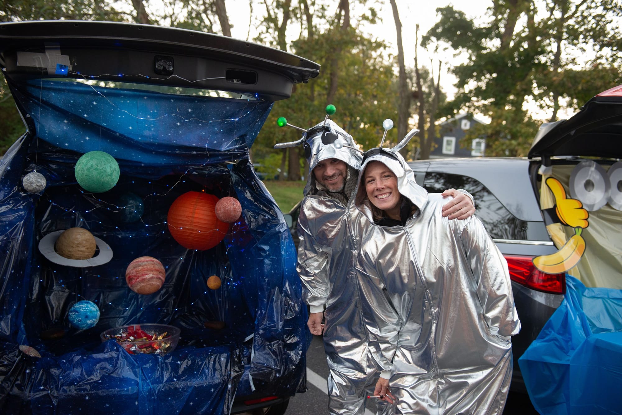 Two people dressed as aliens pose in front of their solar system-themed trunk at Glover School’s Trunk or Treat.