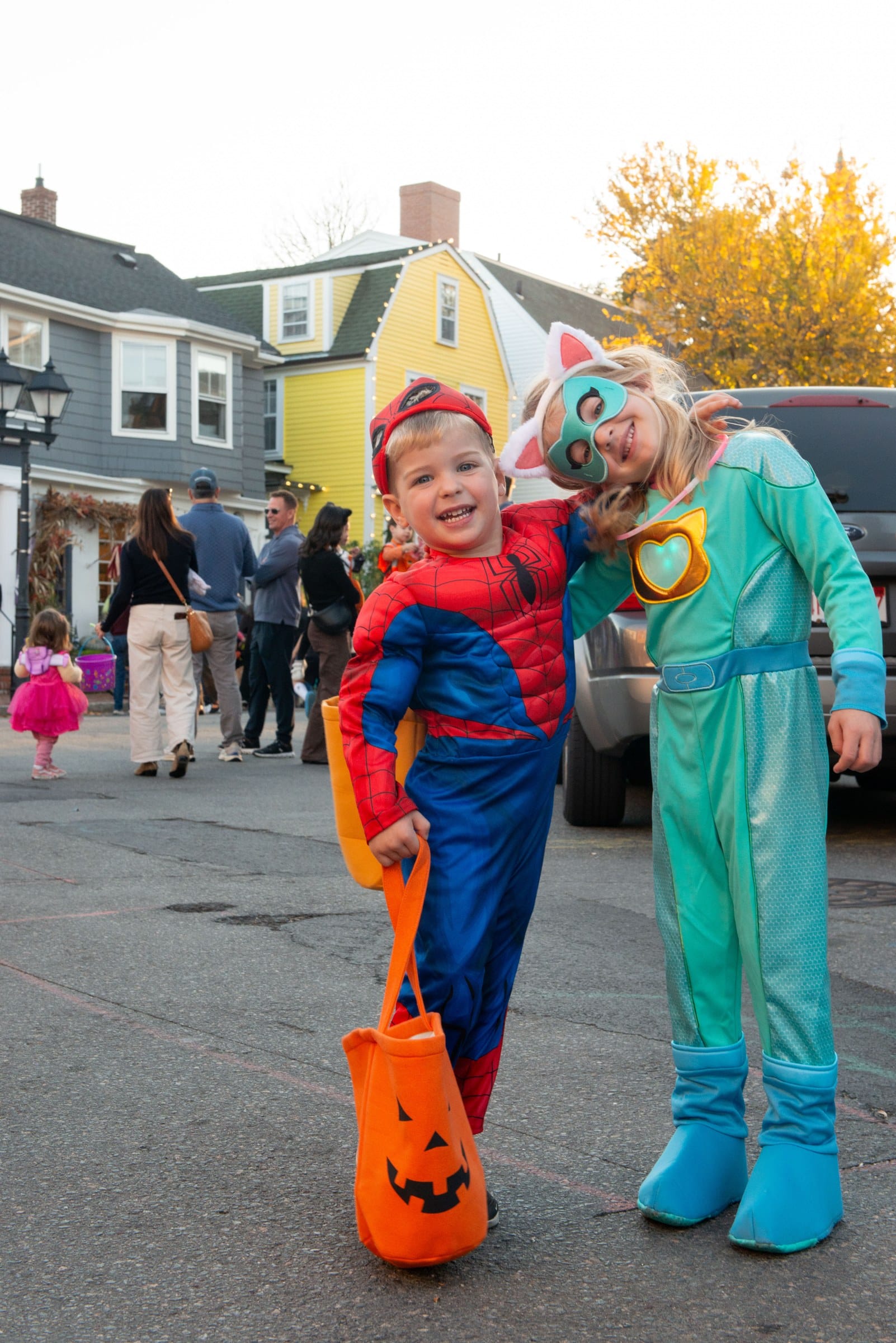 Child in a Spider-Man costume and a child in a cat mask and green suit pose together