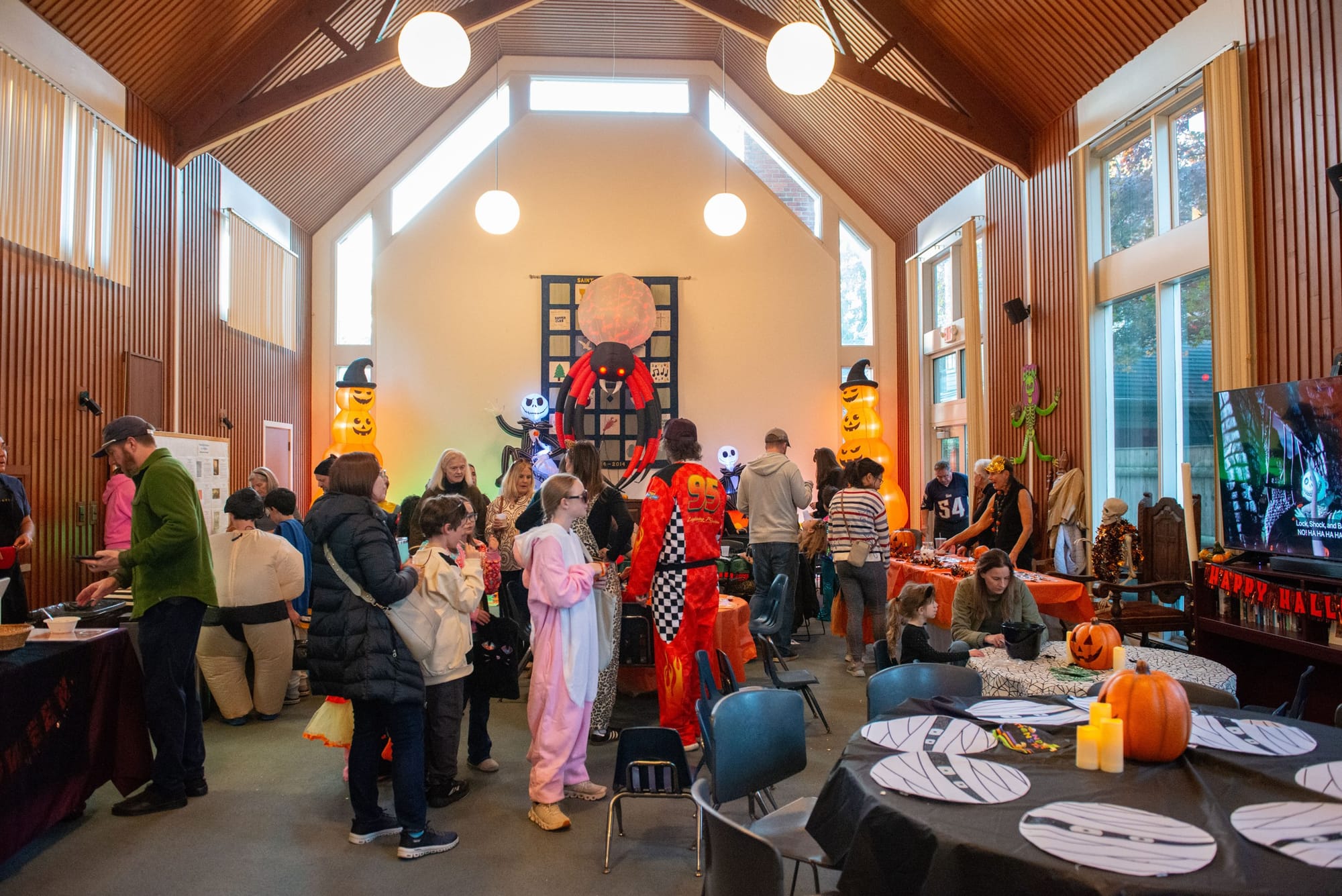 Families mingle in a wood-paneled hall decorated for Halloween