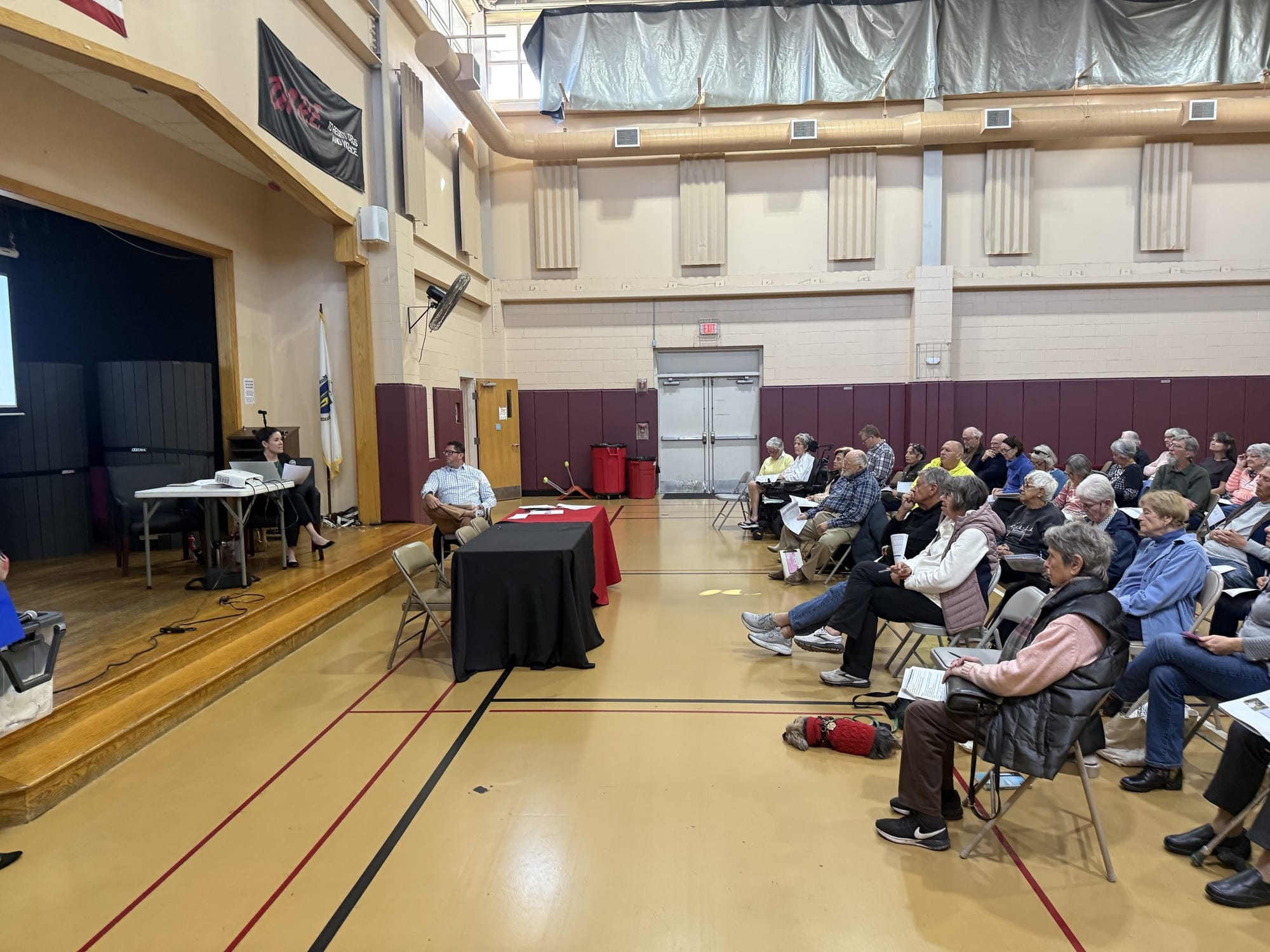 Rows of seniors holding handouts face a stage where Molly Teets sits at a projector table and Todd Laramie sits beside it