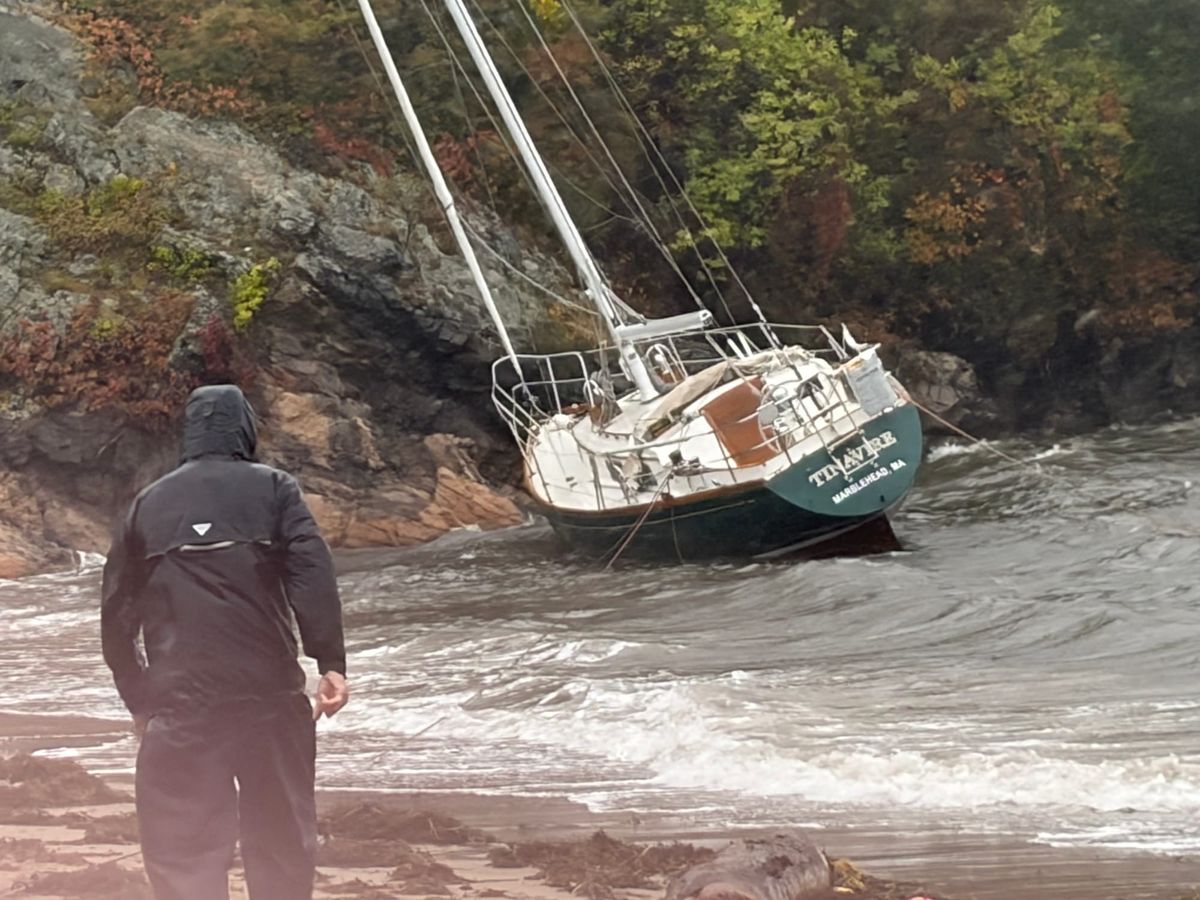 A sailboat sits aground on the beach at Riverhead on Sunday as waves break around its hull